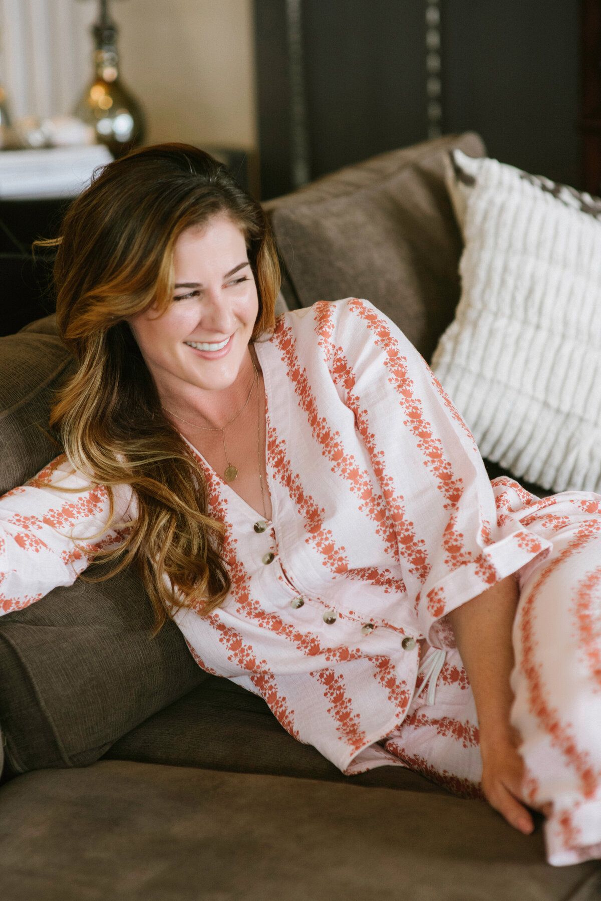 Smiling woman in striped pajamas lounging on a sofa