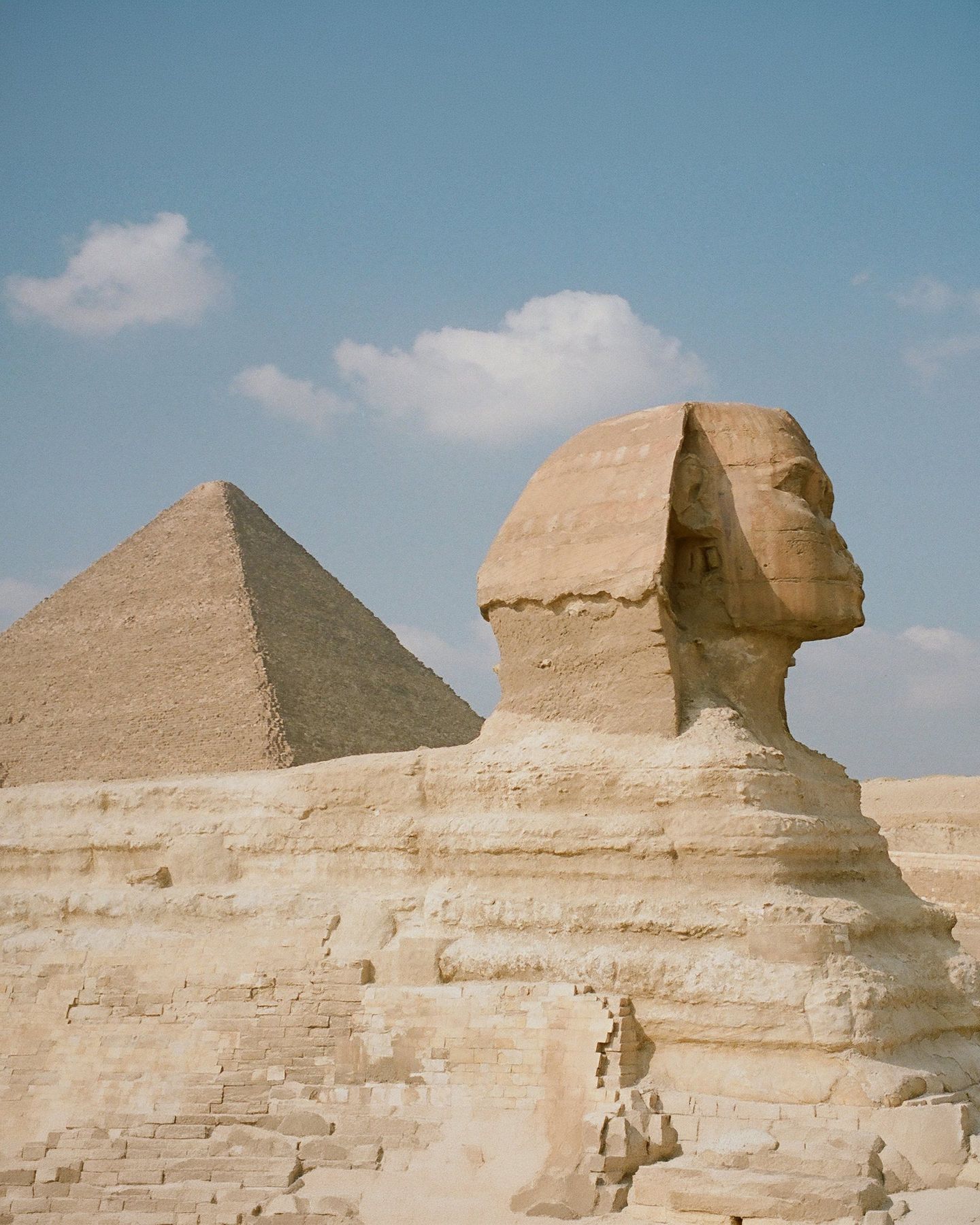 The Great Sphinx and a pyramid under a blue sky in Giza, Egypt